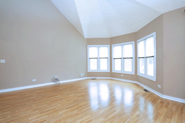 empty room with light hardwood / wood-style floors and vaulted ceiling