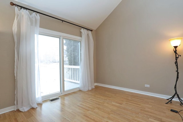 unfurnished room with lofted ceiling and light wood-type flooring