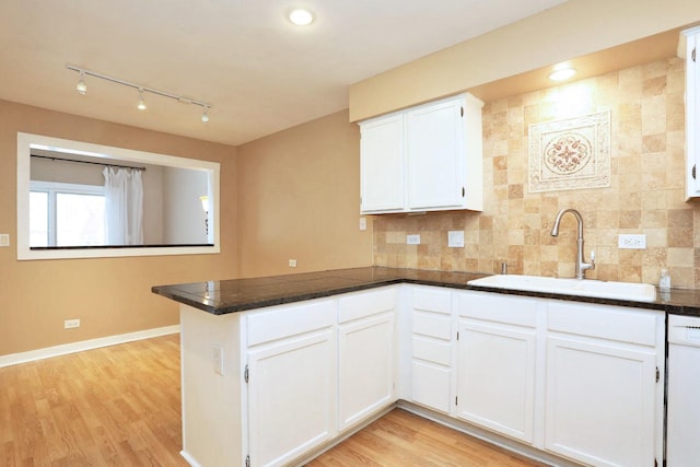 kitchen with kitchen peninsula, white cabinetry, sink, and light wood-type flooring