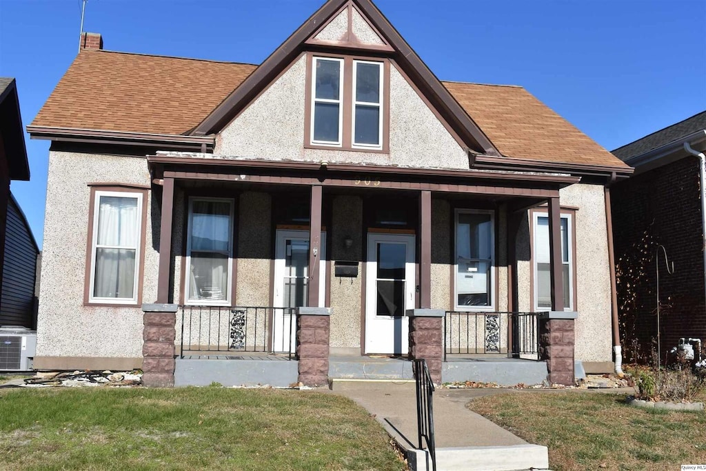 view of front of house with cooling unit, covered porch, and a front lawn