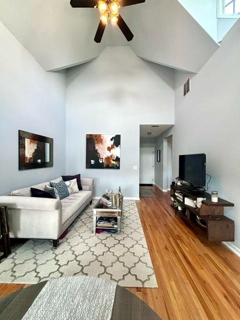 living room featuring hardwood / wood-style floors, high vaulted ceiling, and ceiling fan