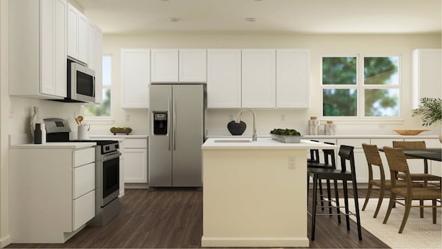 kitchen with a kitchen island with sink, sink, dark hardwood / wood-style floors, white cabinetry, and stainless steel appliances