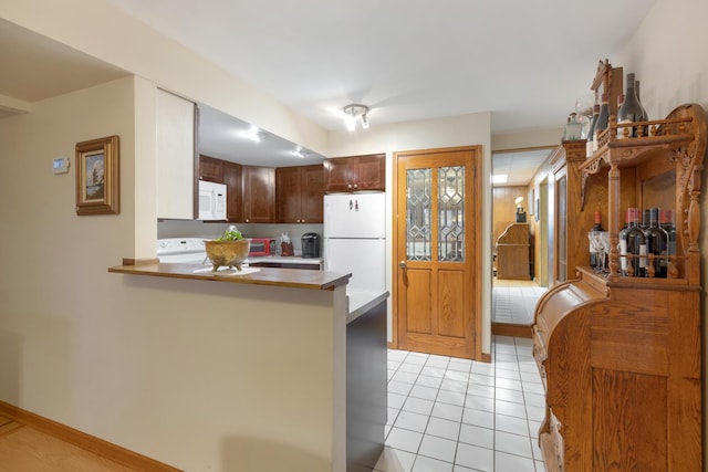 kitchen featuring white appliances, kitchen peninsula, and light tile patterned floors