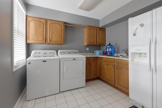 clothes washing area with washer and clothes dryer, cabinets, light tile patterned floors, and sink