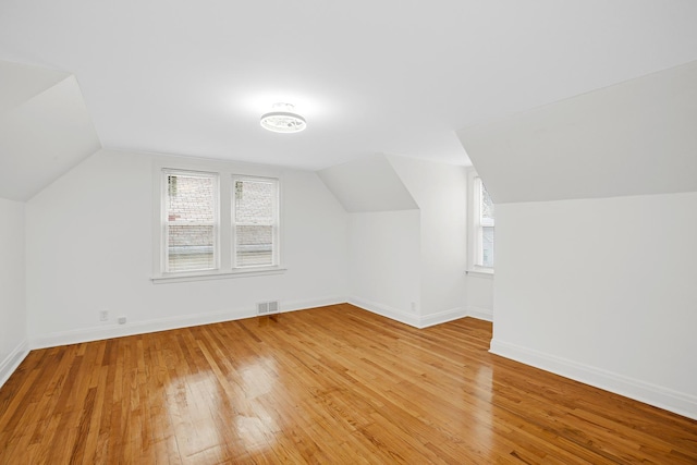 additional living space featuring vaulted ceiling and light hardwood / wood-style flooring