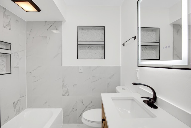 full bathroom featuring tiled shower / bath, vanity, tile walls, and toilet