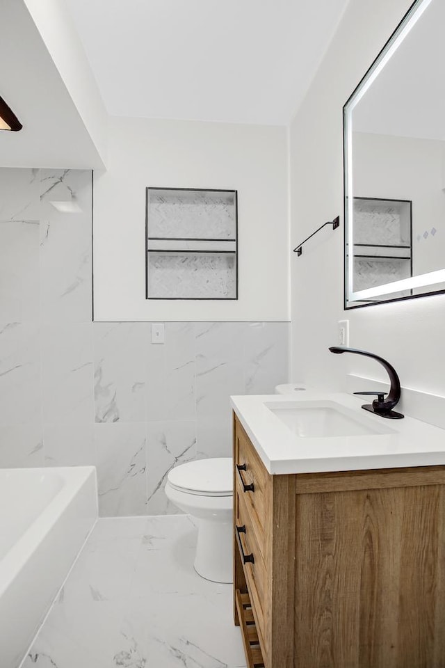 bathroom with vanity, toilet, and tile walls