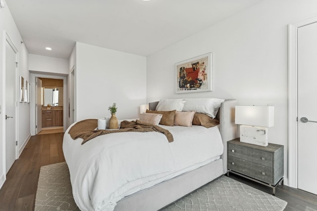 bedroom with ensuite bath and dark hardwood / wood-style flooring