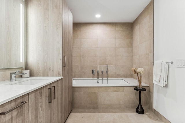 bathroom with tile patterned flooring, vanity, and tiled tub