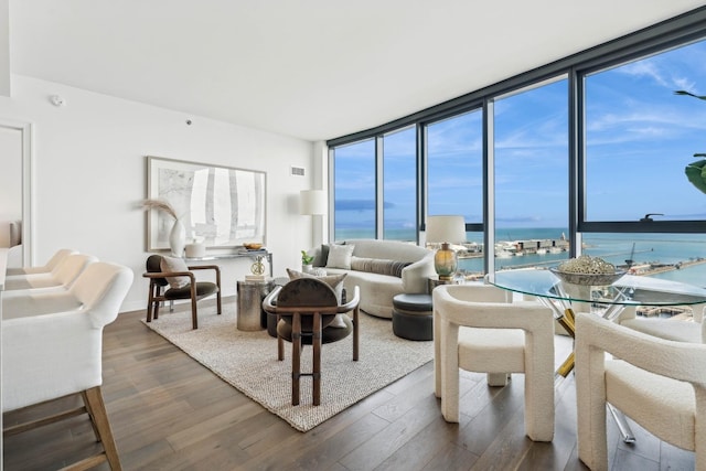 living room with floor to ceiling windows, dark hardwood / wood-style flooring, and a water view