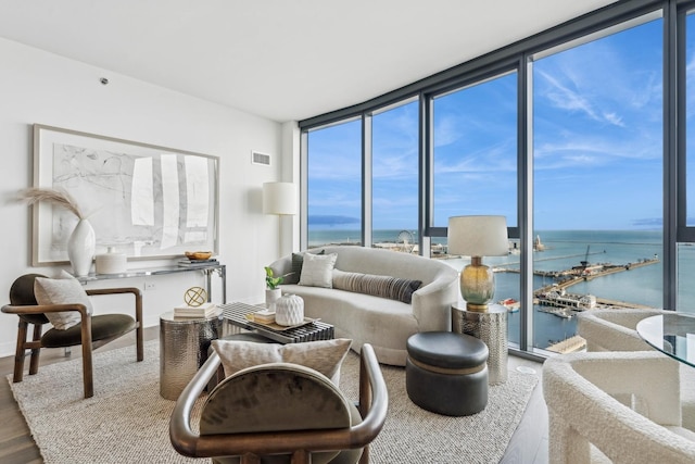 living room with expansive windows, a water view, and hardwood / wood-style flooring