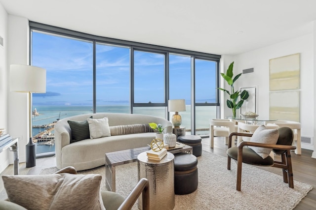 living room featuring a water view, light hardwood / wood-style flooring, and floor to ceiling windows