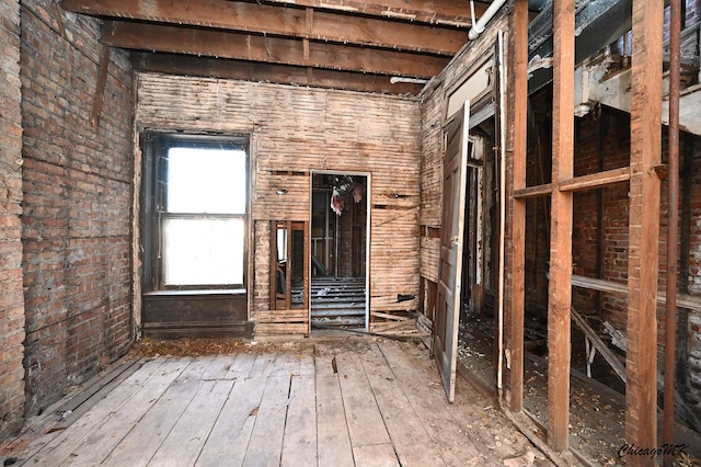 miscellaneous room with wood-type flooring and brick wall