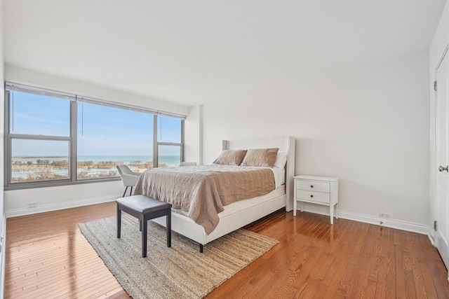 bedroom with a water view and hardwood / wood-style flooring