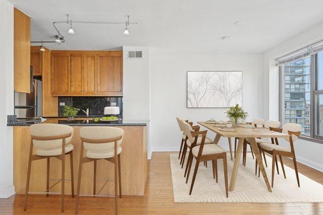 kitchen with backsplash, stainless steel refrigerator, light hardwood / wood-style flooring, and rail lighting