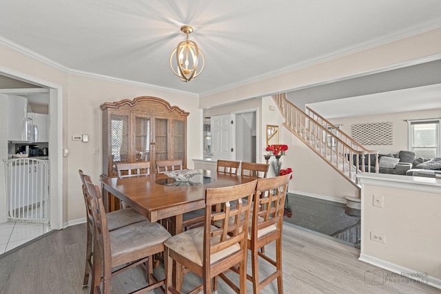 dining area featuring a chandelier, ornamental molding, and light hardwood / wood-style flooring