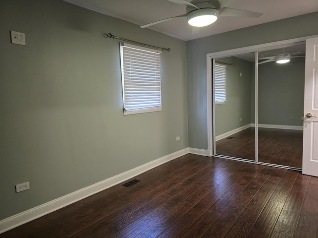 unfurnished bedroom with a closet, multiple windows, ceiling fan, and dark hardwood / wood-style flooring