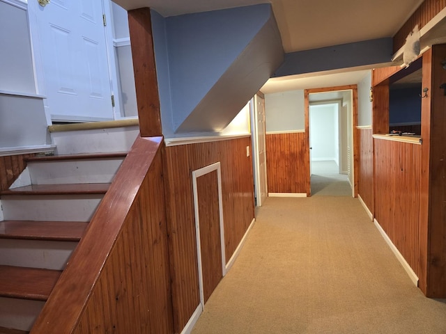 corridor featuring light carpet and wooden walls