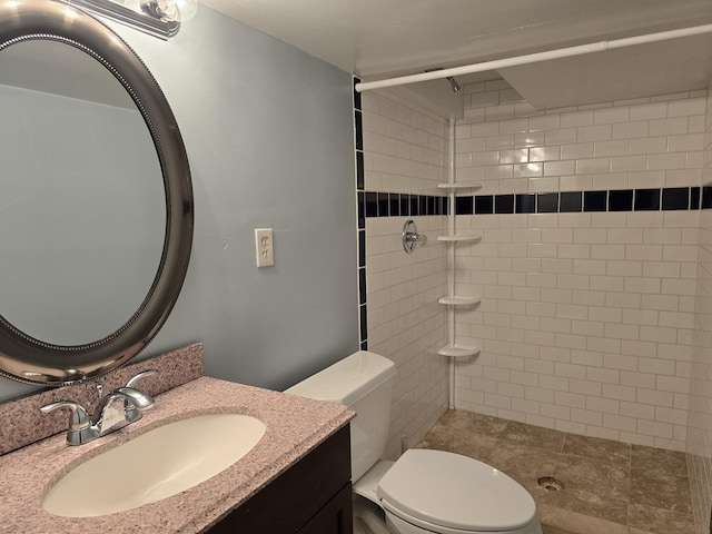 bathroom featuring tiled shower, vanity, and toilet