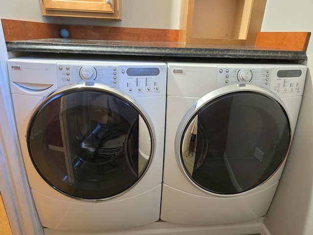 laundry room featuring washing machine and clothes dryer and cabinets