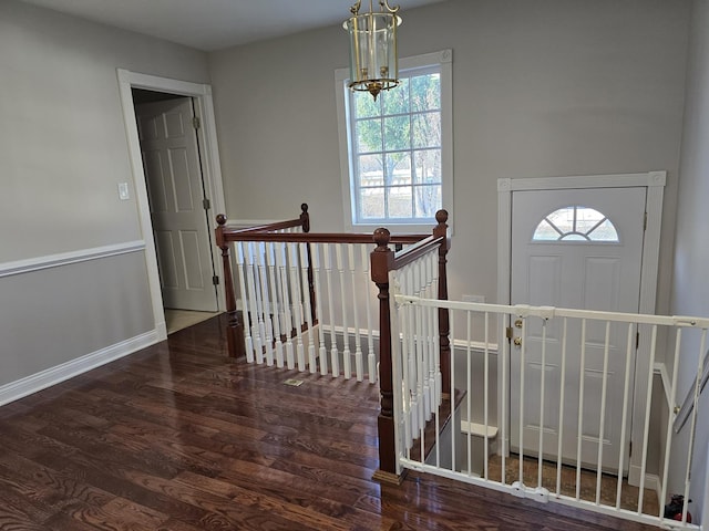 entrance foyer with a chandelier, a wealth of natural light, and dark wood-type flooring