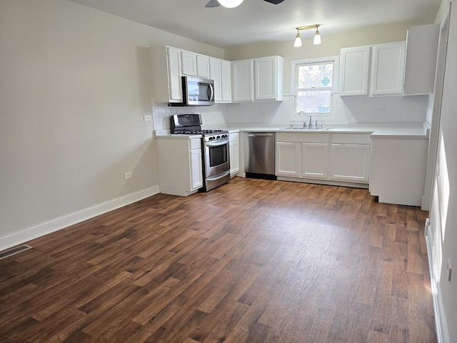 kitchen featuring backsplash, white cabinets, sink, dark hardwood / wood-style flooring, and stainless steel appliances