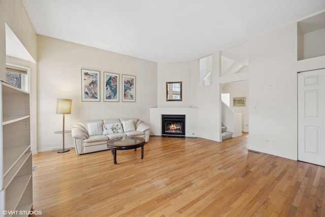 living room featuring a towering ceiling and light hardwood / wood-style flooring