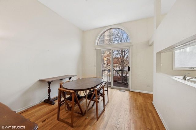 dining room featuring light wood-type flooring and high vaulted ceiling