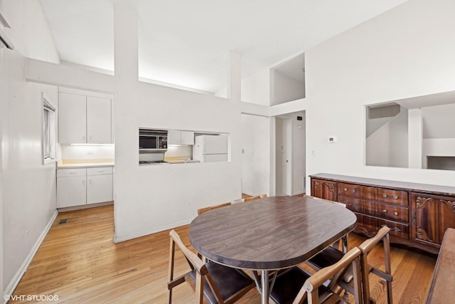 dining area featuring a high ceiling and light wood-type flooring