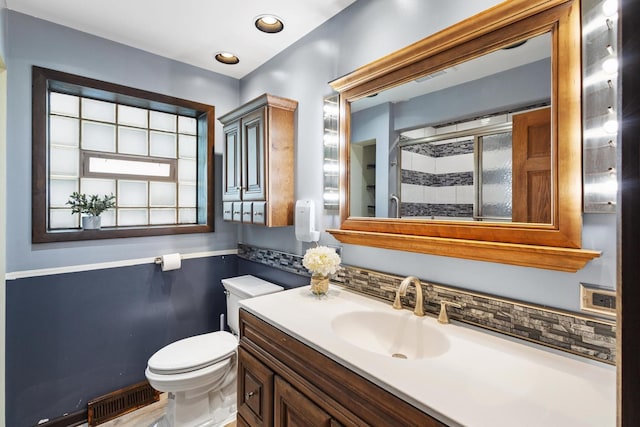 bathroom with vanity, toilet, and a shower with door