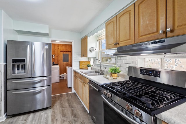 kitchen with tasteful backsplash, stainless steel appliances, sink, light hardwood / wood-style flooring, and washer / clothes dryer