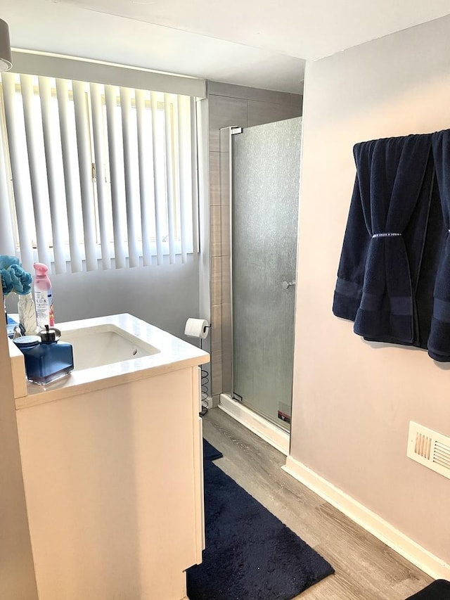 bathroom featuring lofted ceiling, vanity, hardwood / wood-style flooring, and a shower with shower door