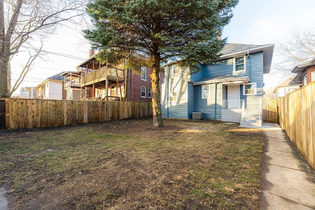 rear view of house featuring central AC unit and a lawn