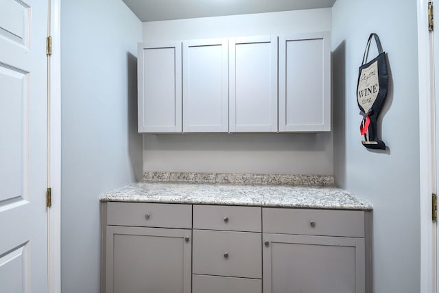 bar featuring gray cabinetry and light stone countertops