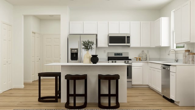 kitchen with light wood finished floors, a breakfast bar area, stainless steel appliances, white cabinetry, and a sink