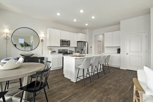 kitchen featuring stainless steel appliances, a kitchen island with sink, white cabinets, and dark hardwood / wood-style floors