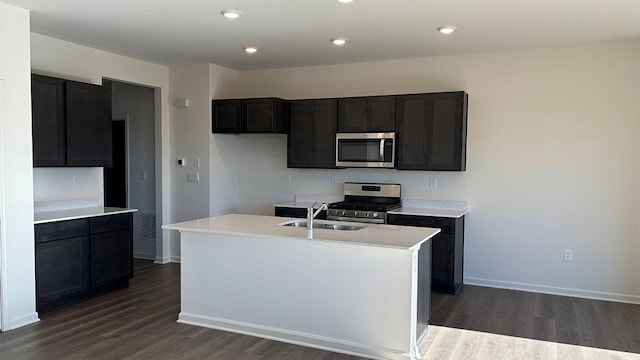 kitchen with stainless steel appliances, an island with sink, sink, and dark hardwood / wood-style flooring