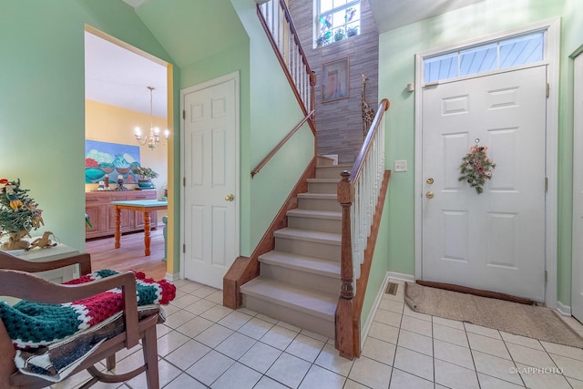 tiled entryway with lofted ceiling and a notable chandelier