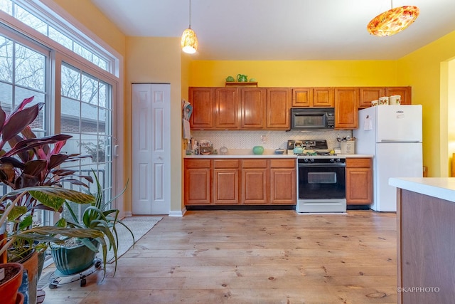 kitchen with decorative light fixtures, light wood-type flooring, white appliances, and decorative backsplash