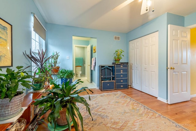 interior space featuring a closet, ensuite bathroom, light hardwood / wood-style flooring, and ceiling fan