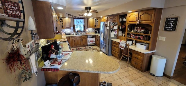 kitchen with decorative backsplash, light stone counters, stainless steel appliances, ceiling fan, and light tile patterned floors