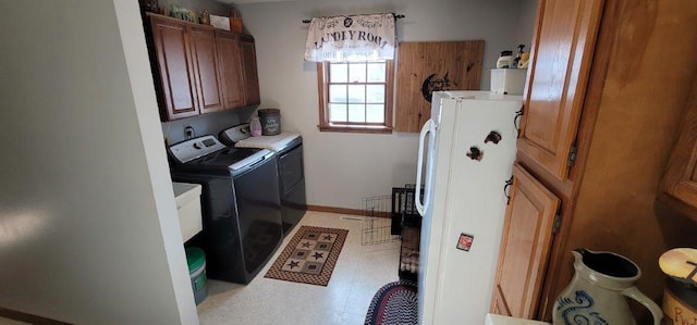 clothes washing area with separate washer and dryer and cabinets