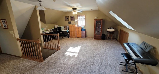 carpeted home office with vaulted ceiling with skylight and ceiling fan