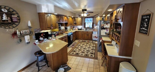 kitchen with kitchen peninsula, a kitchen bar, tasteful backsplash, ceiling fan, and electric range