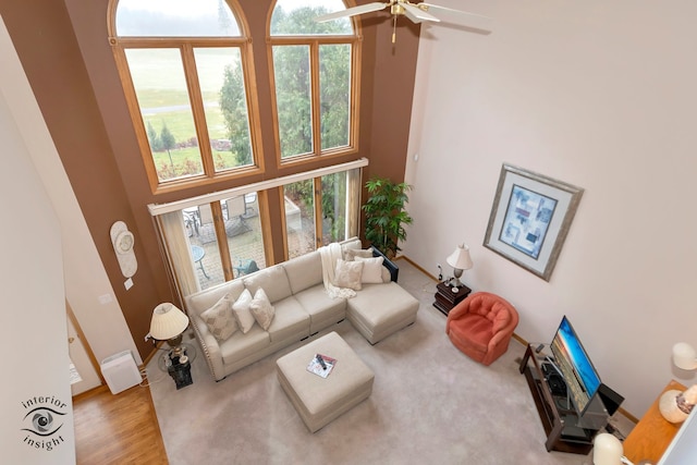 living room featuring a high ceiling, light wood-type flooring, and ceiling fan