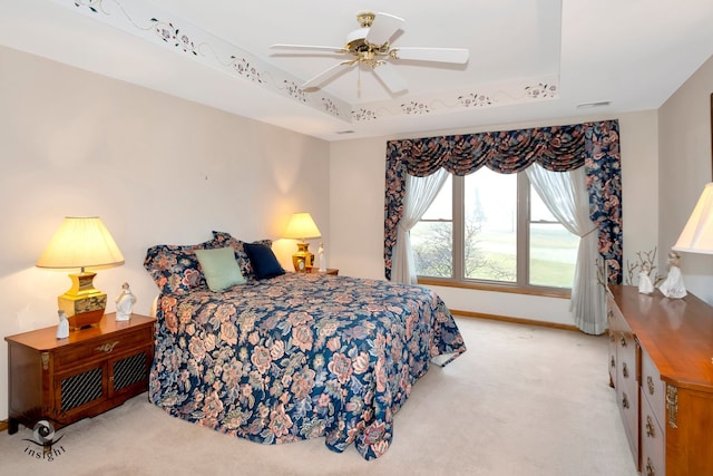 bedroom featuring a raised ceiling, ceiling fan, and light colored carpet