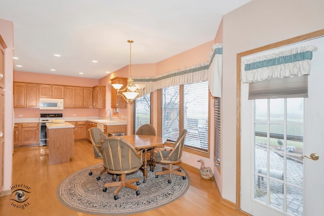 dining area with light wood-type flooring, an inviting chandelier, and sink