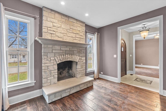 living room with dark hardwood / wood-style flooring and a stone fireplace