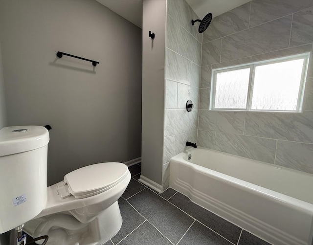 bathroom featuring tile patterned flooring, tiled shower / bath combo, and toilet