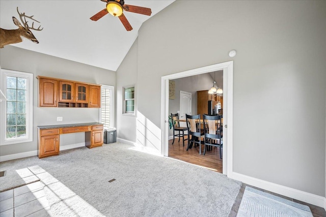 kitchen with ceiling fan with notable chandelier, light carpet, and high vaulted ceiling